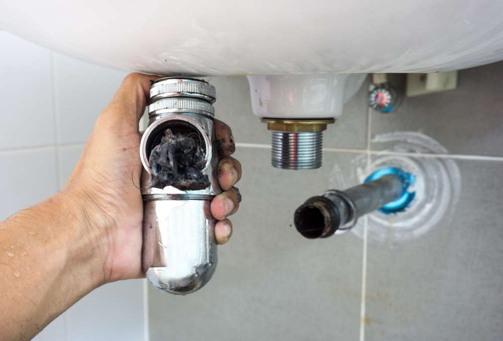 Hand of a plumber holding joints and connections of basin